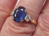 un gros plan de la main d'une personne tenant une bague sertie d'un saphir et d'un diamant