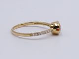 a close up of a gold ring with a red stone on it