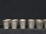a group of silver shot glasses sitting next to each other