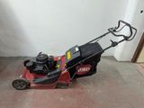 a red and black lawn mower sitting on the floor