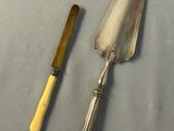 a silver spoon and a yellow handled knife on a table