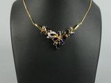 un collier en or orné de cristaux bleus et blancs sur un mannequin noir