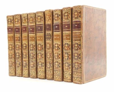 six vieux livres sont alignés sur une surface blanche