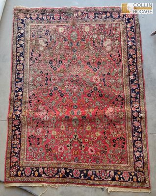 un tapis persan ancien à fond rouge et bordure bleue