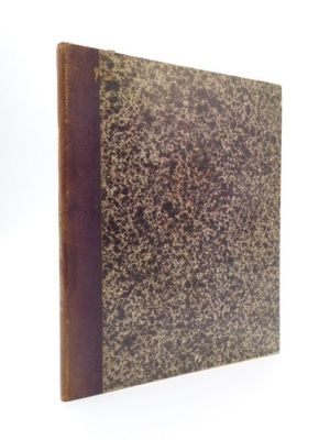 un vieux livre à la couverture brune posé sur une surface blanche