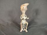 statue représentant une femme assise sur un tabouret, avec un oiseau sur l'épaule