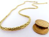 un gros plan d'une pièce de monnaie et d'un collier posés sur une surface blanche