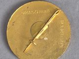 an image of a close up of a gold medal on a gray surface