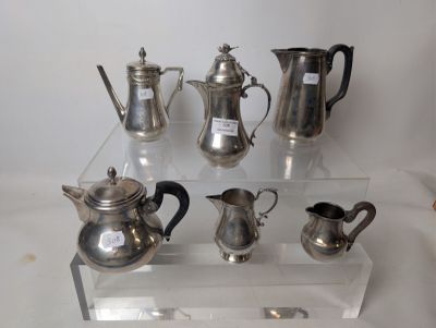 a lot of silver teapots and coffee pots on a clear shelf