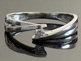 silver ring with a single diamond on top of a black surface