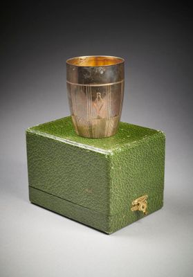 une boîte verte surmontée d'une coupe argentée, posée sur une surface grise