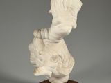 a white marble sculpture of a woman holding a child on a wooden base