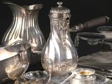 un plateau en argent avec une carafe en argent et un plateau en argent sur lequel sont disposés des couverts en argent