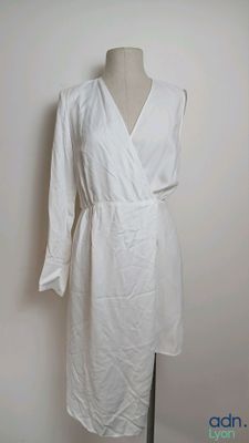 white dress on a mannequin stand against a white wall