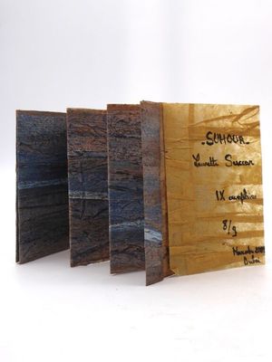 trois morceaux de bois portant des inscriptions, posés sur une surface blanche