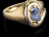 gros plan d'une bague en or avec une pierre bleue