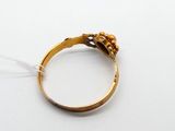 une bague en or ornée d'une fleur, posée sur un fond blanc