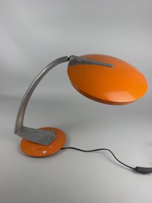 an orange desk lamp on a white surface with a black cord