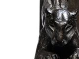 statue of a bull resting on a rock in front of a sign
