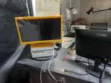 yellow and black computer monitor sitting on top of a desk next to a laptop computer