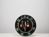 une assiette noire décorée d'oranges et de feuilles