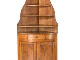 une armoire d'angle en bois surmontée d'une étagère