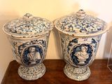 two blue and white vases on a wooden table with a picture of a man and a woman