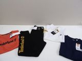 Trois paires de t-shirts et un pantalon sont posés sur une table