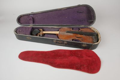 un violon dans son étui, à côté d'une chaussure rouge