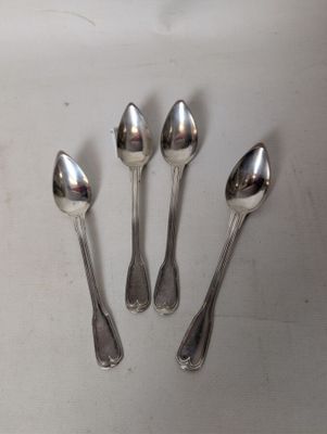 four silver spoons are arranged in a row on a white surface