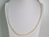 collier composé de perles blanches et dorées, présenté sur un mannequin blanc