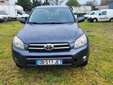 Une Toyota RAV noire est garée dans un champ herbeux.