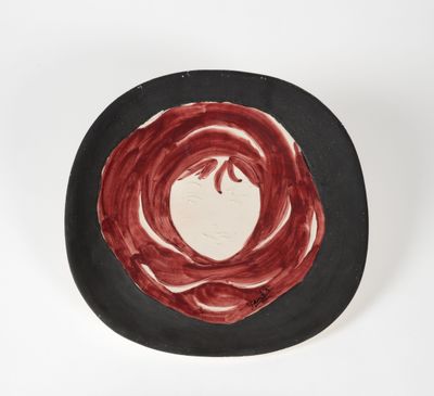 une assiette noire ornée d'un motif rouge et blanc