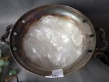 a silver bowl with plastic wrap on it next to grapes