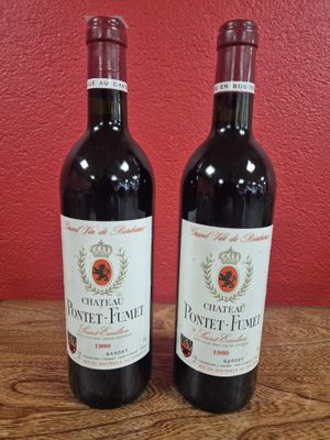 Deux bouteilles de vin sont posées sur une table devant un mur rouge.