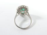 a close up of a diamond and emerald ring on a white surface