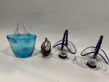 trois vases en verre bleu posés les uns à côté des autres sur une surface blanche