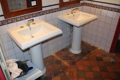 deux lavabos dans une salle de bains dont les murs et le sol sont carrelés