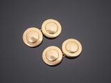 three gold plated buttons on a black surface
