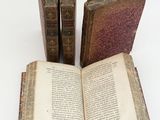 several old books are stacked on top of each other on a white surface