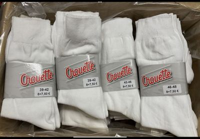 four pairs of white socks are in a box on a table