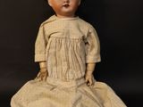 an old doll sitting on a black surface wearing a hat and dress