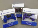 Trois manettes PS4 sont dans leurs emballages, posées sur une table.