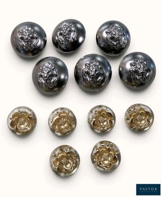six boutons en verre noir et doré sur une surface blanche