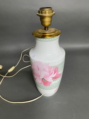 a white vase with a pink flower on it and a gold lamp