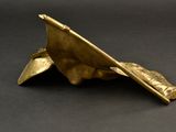 brass sculpture of a hand holding a book on a black surface
