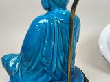 a blue statue of a person holding a staff