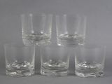 six glasses of different sizes and shapes are lined up on a gray surface