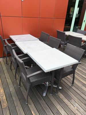 des tables et des chaises sur une terrasse en bois, avec un mur rouge en arrière-plan