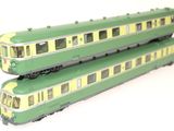 two green and yellow train cars sitting side by side